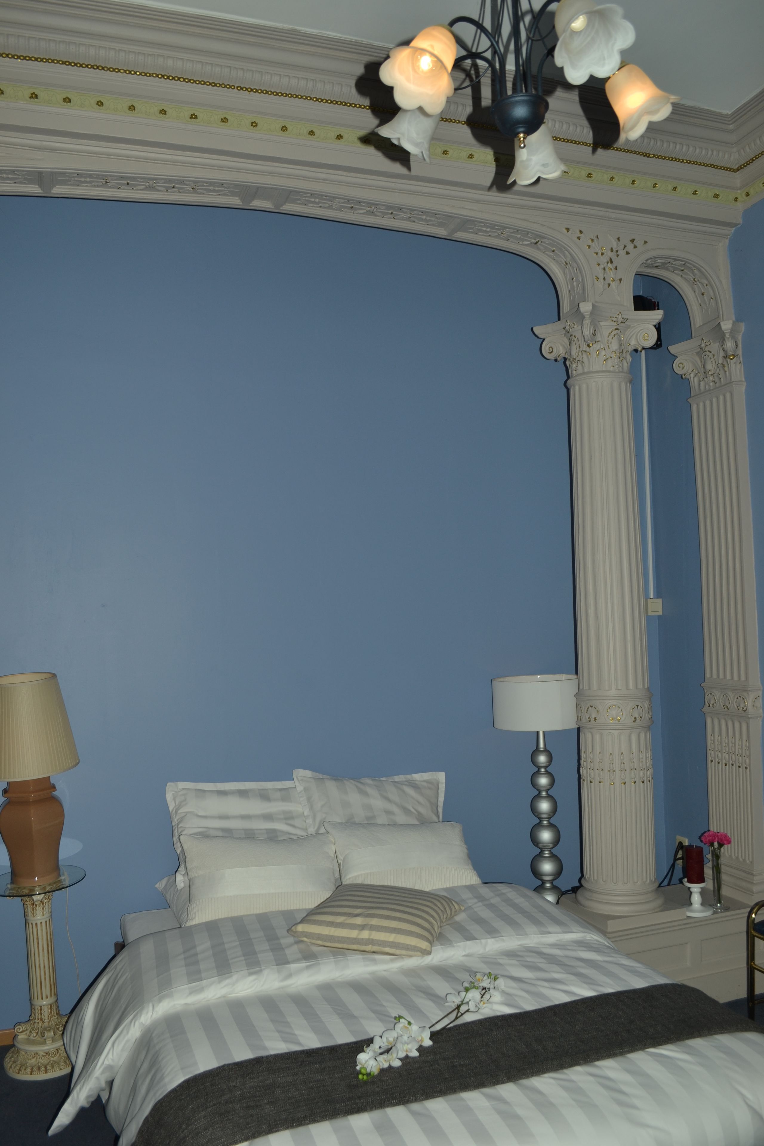 A bedroom with a bed, two bedside lamps, a nightstand, and a decorative ceiling.