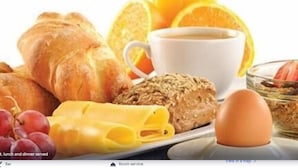 Un desayuno con croissants, una taza de café, un tazón de cereal, uvas y un huevo cocido.