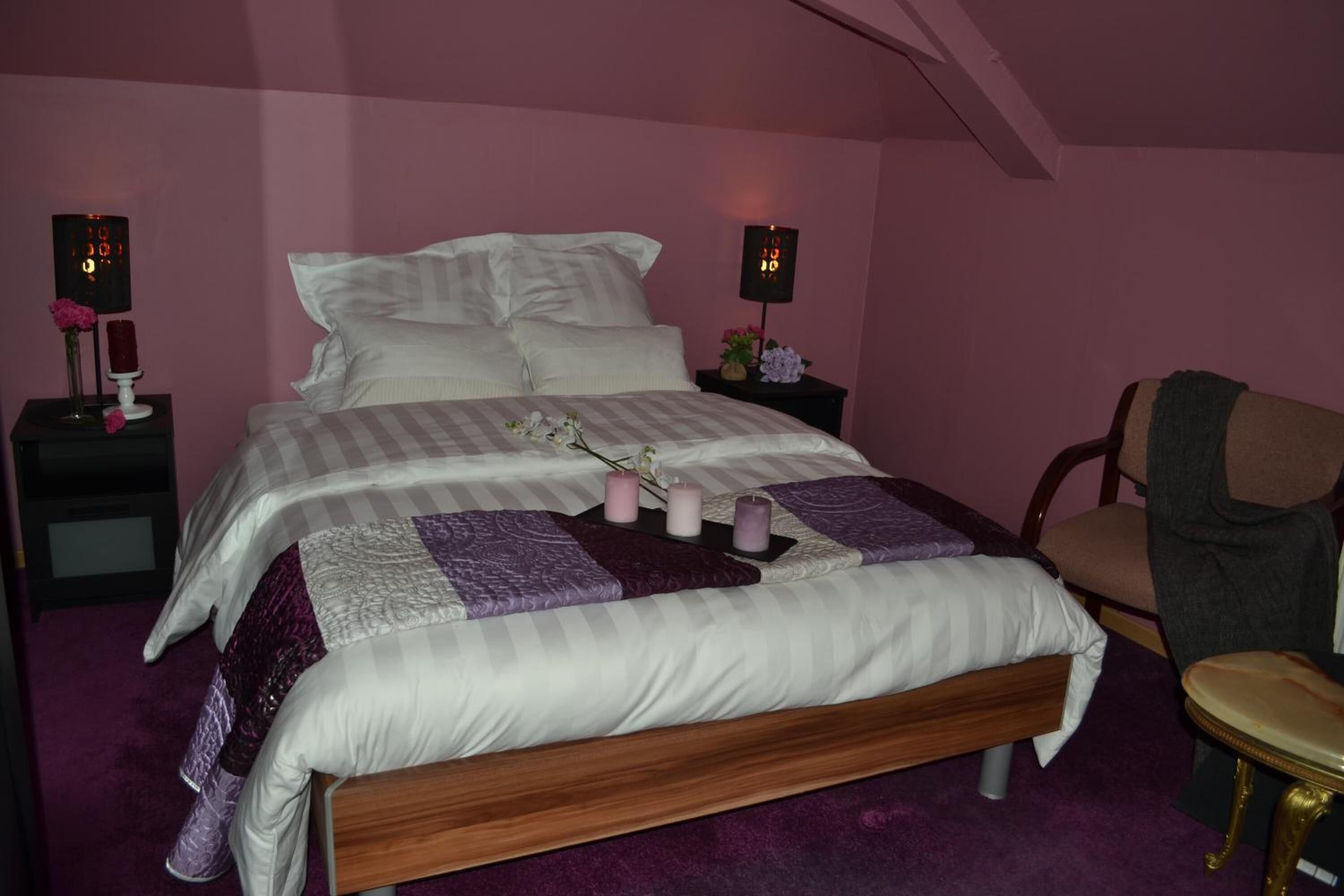 Un dormitorio con una cama grande, dos mesitas de noche, una silla y una pequeña mesa.