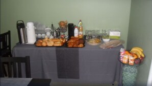Una mesa con diferentes alimentos y bebidas, como pan, pasteles y frutas.