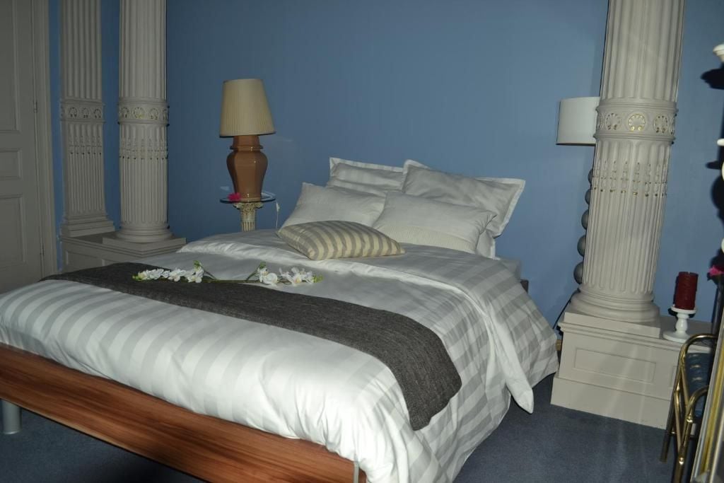 A bedroom with a bed, pillows, a bedside table with a lamp, and a nightstand with a candle.
