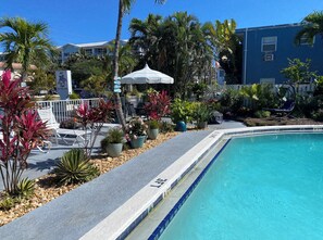 Een buitenzwembad, parasols bij het zwembad en ligstoelen