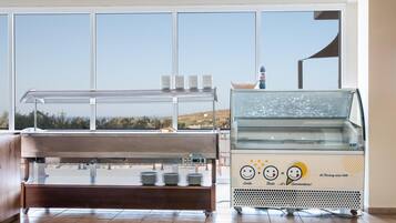 A buffet area with a glass display case and a counter with plates and cups.