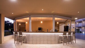 A modern kitchen with a curved island, bar stools, and a coffee machine. - Chrissy's Paradise (Malevizi)