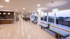A spacious lobby with a reception desk, seating area, and large windows offering a view of the outdoors. - Chrissy's Paradise (Malevizi)