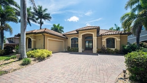 A two-story house with a tiled roof, a driveway, and palm trees. - 4BR gulf access villa w/heated pool & hot tub! Villa Francesca - SWFL Rentals (Cape Coral)