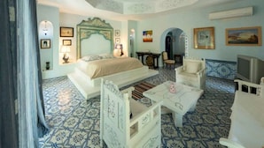 A hotel room with a bed, a desk, a chair, a television, and a patterned floor. - Villa HEIWA - havre de paix (Hammamet)