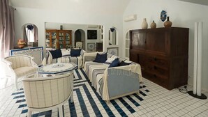 A living room with a checkered floor, a sofa set, a wooden cabinet, and a mirror. - Villa HEIWA - havre de paix (Hammamet)