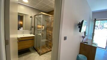 Un baño moderno con ducha de vidrio, tocador de madera y un espejo grande.