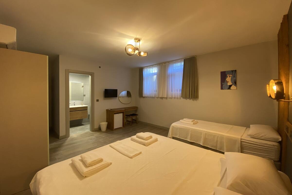 Een hotelkamer met twee bedden, een bureau, een stoel, een televisie en een raam met gordijnen.