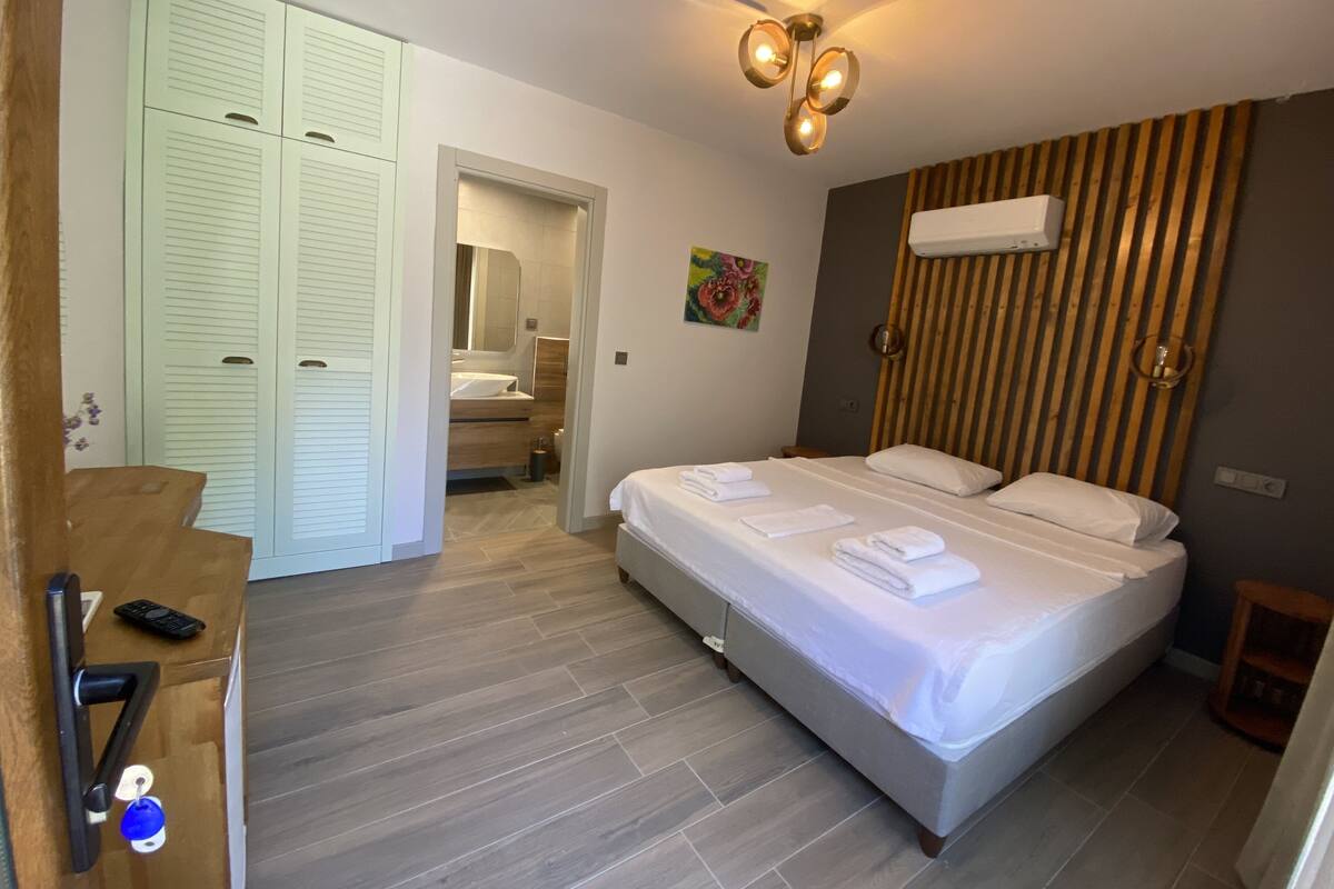 Een hotelkamer met een bed, een houten garderobe, een badkamer en een plafondlamp.