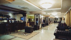 A spacious lobby with a bar area, leather sofas, and a chandelier. - Solva Resort & SPA (Poliana)