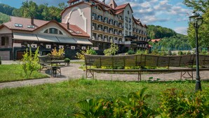 A multi-story hotel with a central courtyard, outdoor seating, and a view of a mountainous landscape. - Solva Resort & SPA (Poliana)