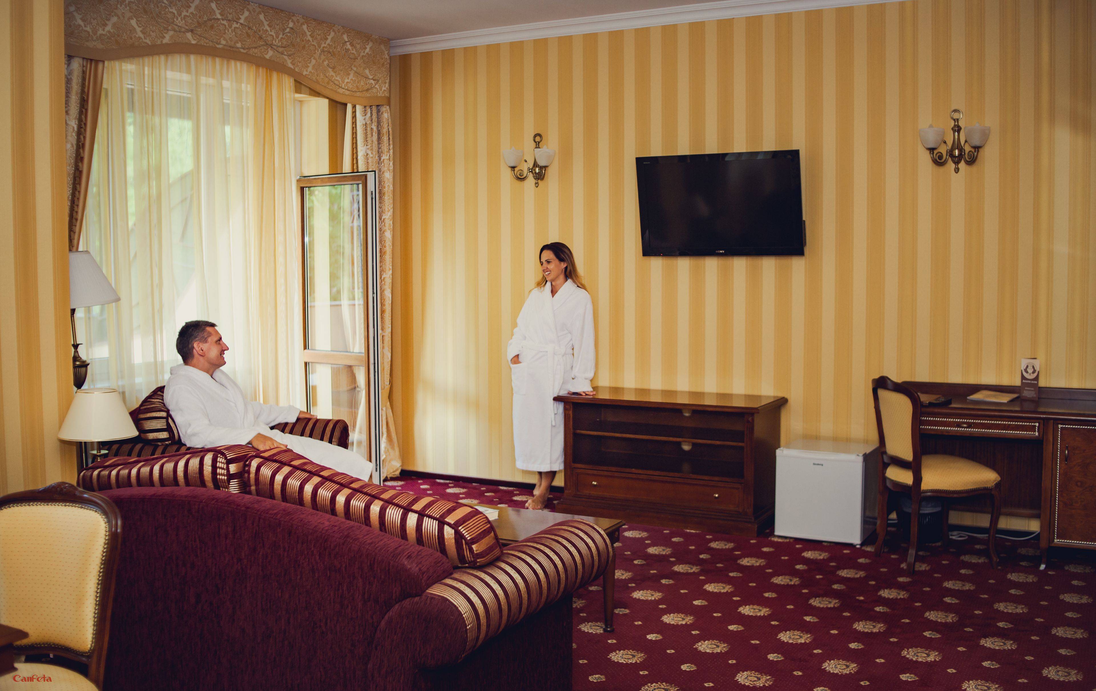 Una habitación de hotel con una cama, un sofá, un escritorio y una televisión.