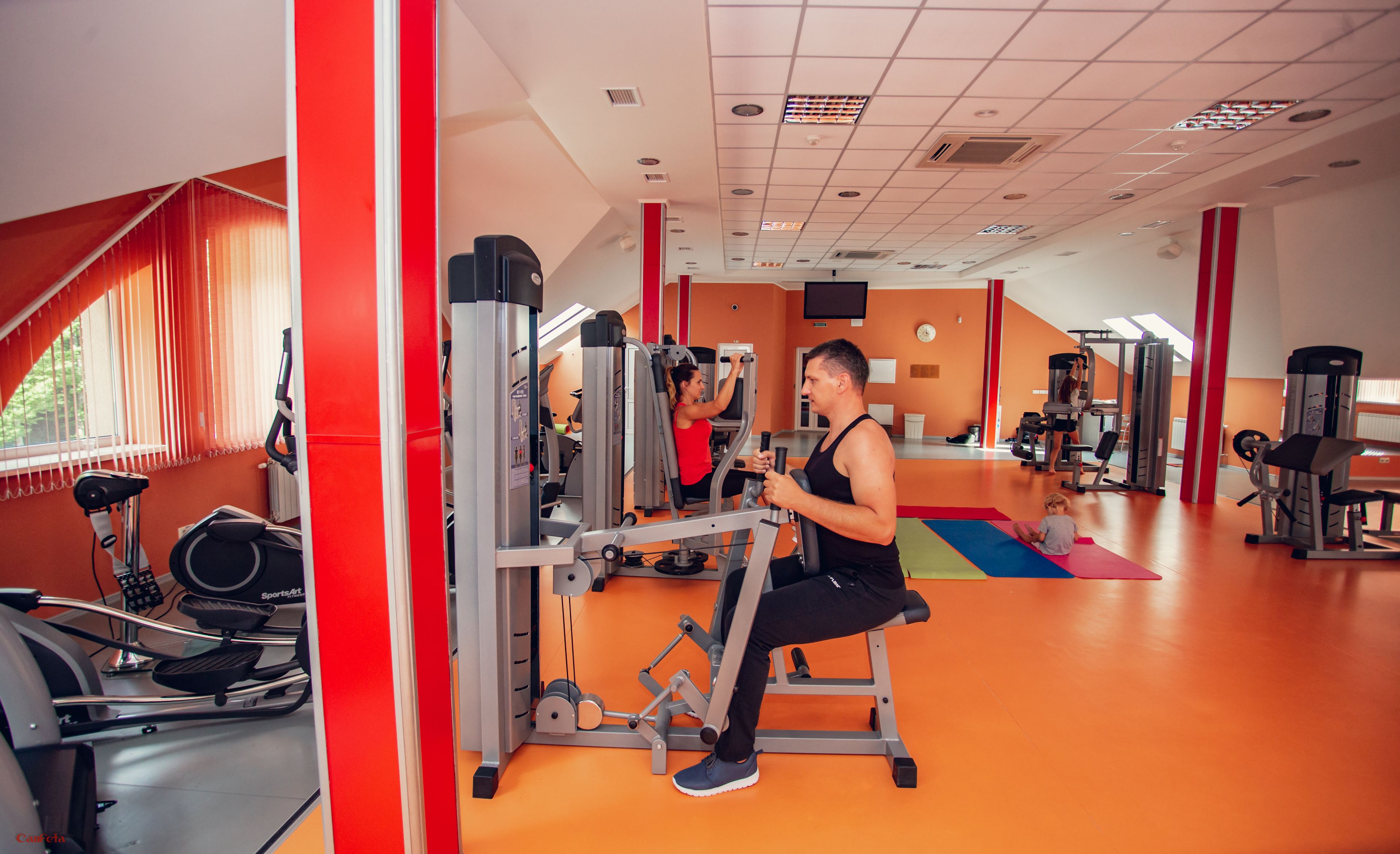 Une salle de sport équipée de matériel d’exercice, d’un tapis de course et d’un miroir.