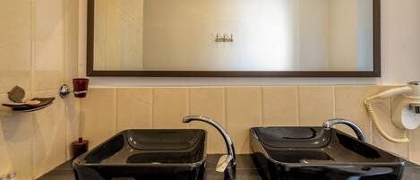Un baño con dos lavamanos negros, un espejo grande y un perchero para toallas.
