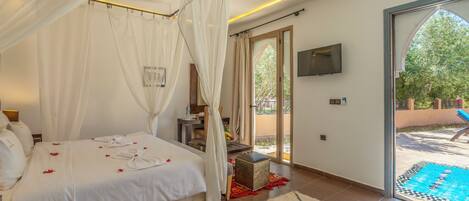 Quarto com cama, televisão e varanda com piscina.