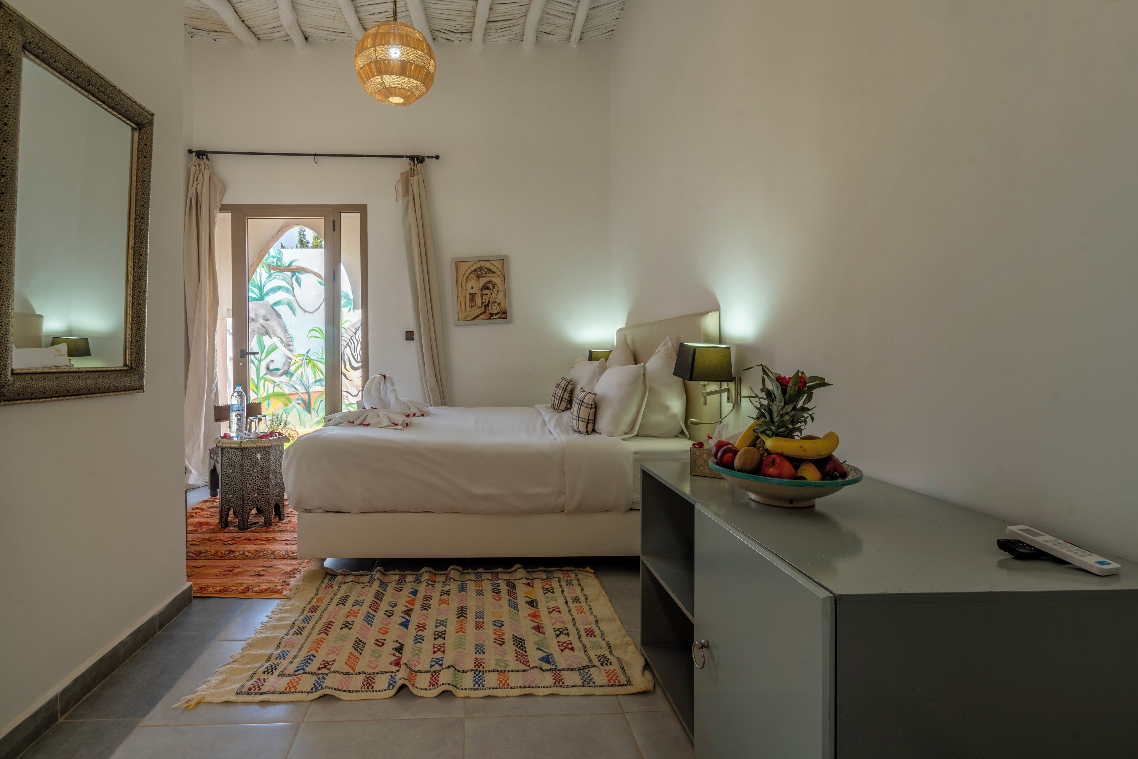Une chambre à coucher avec un lit, une table de chevet, une lampe et un panier de fruits.