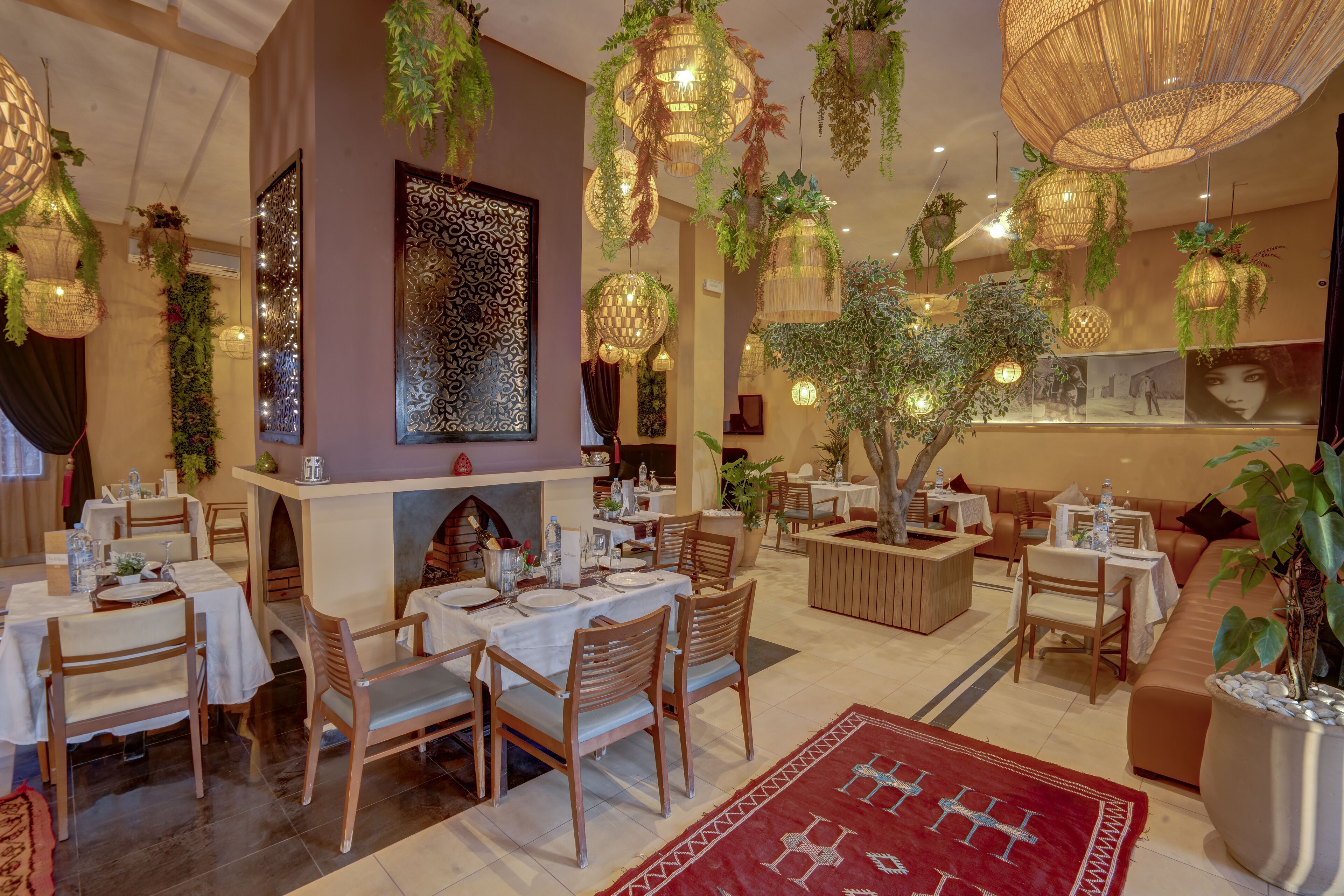 A restaurant with multiple dining areas, hanging plants, and decorative lighting fixtures.
