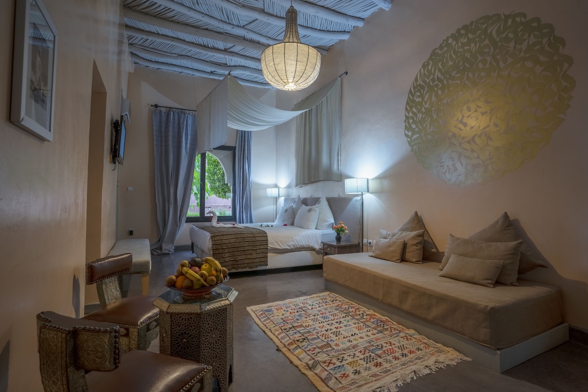 Une chambre à coucher comprenant un lit, des tables de chevet, un canapé, une chaise et un élément décoratif mural.