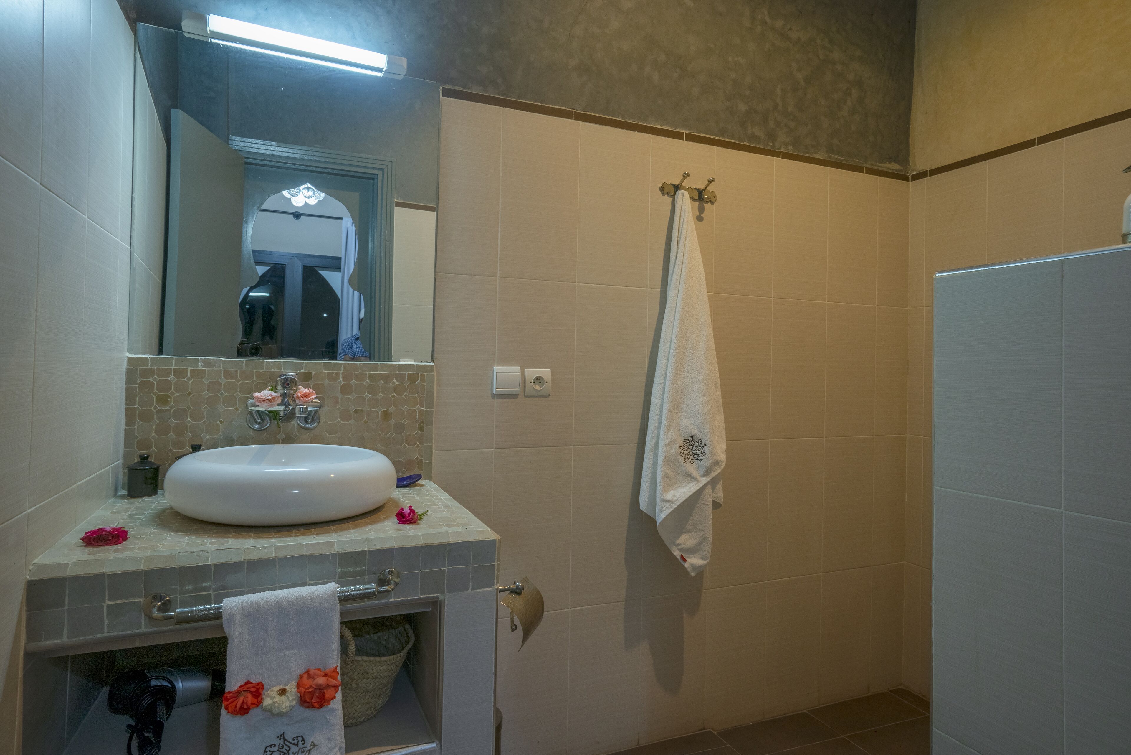 A bathroom with a sink, mirror, towel rack, and a shower area.