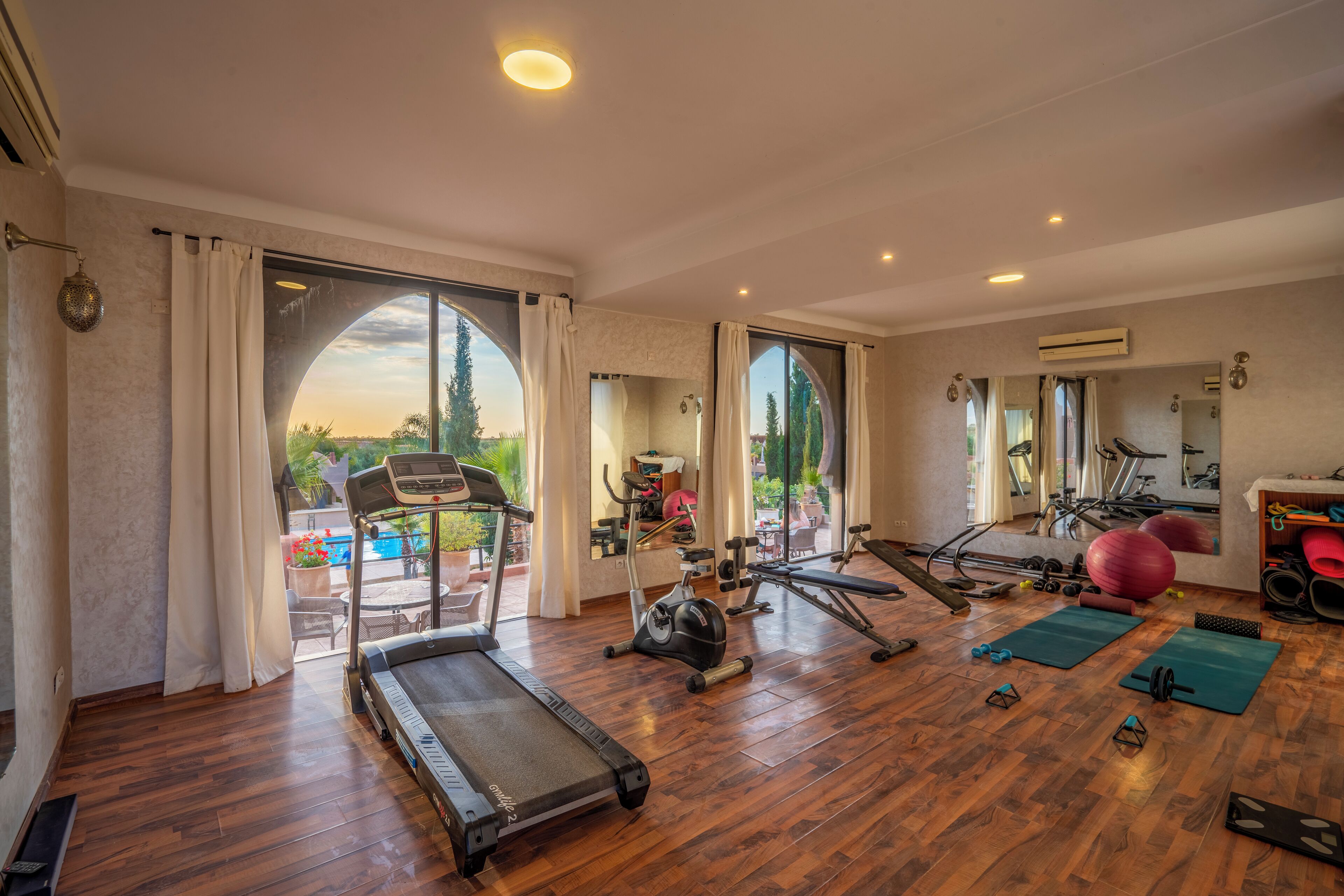 A spacious gym with exercise equipment, large windows, and a view of the outdoors.