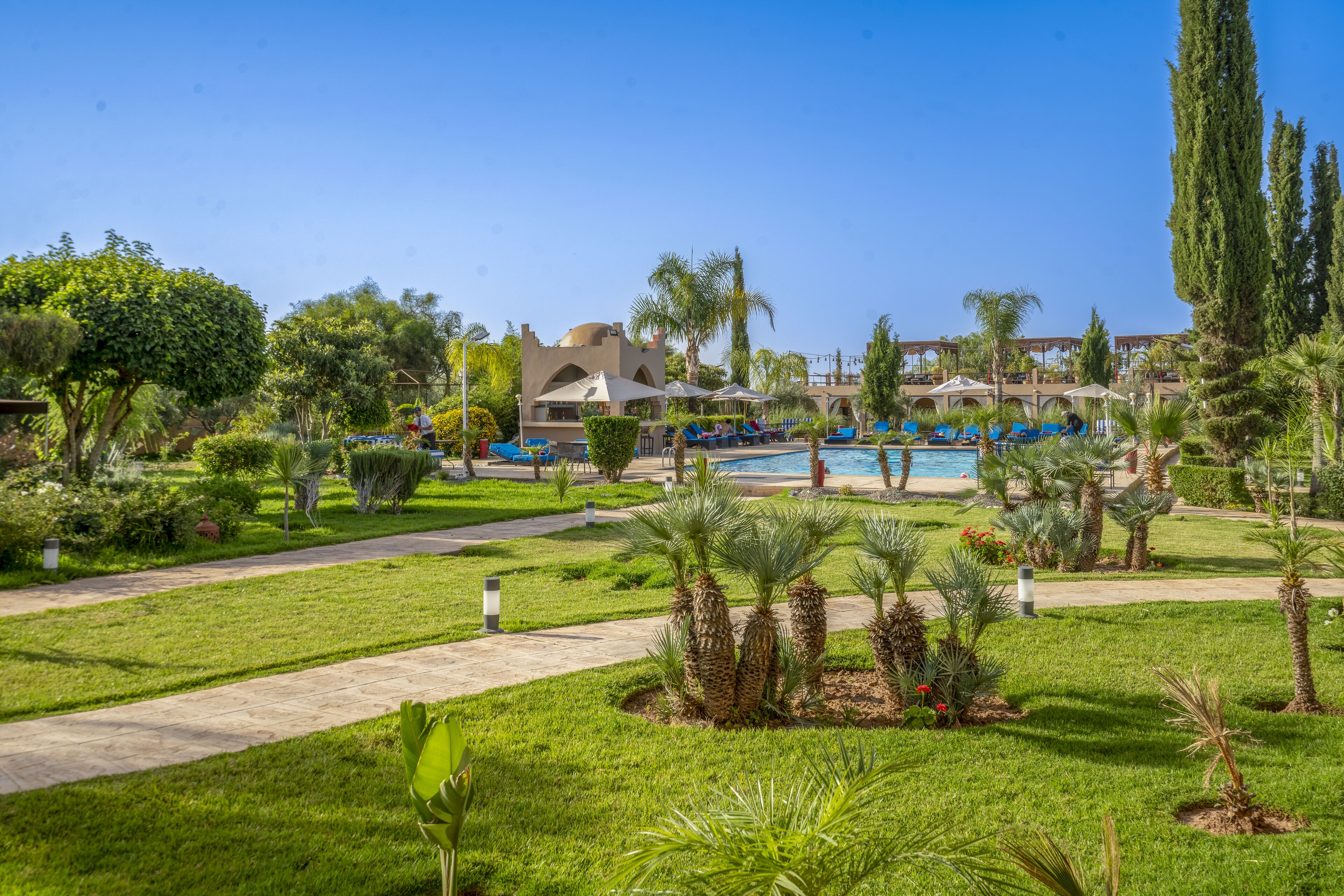 Un resort con piscina, palmeras y un sendero que conduce al área de la piscina.
