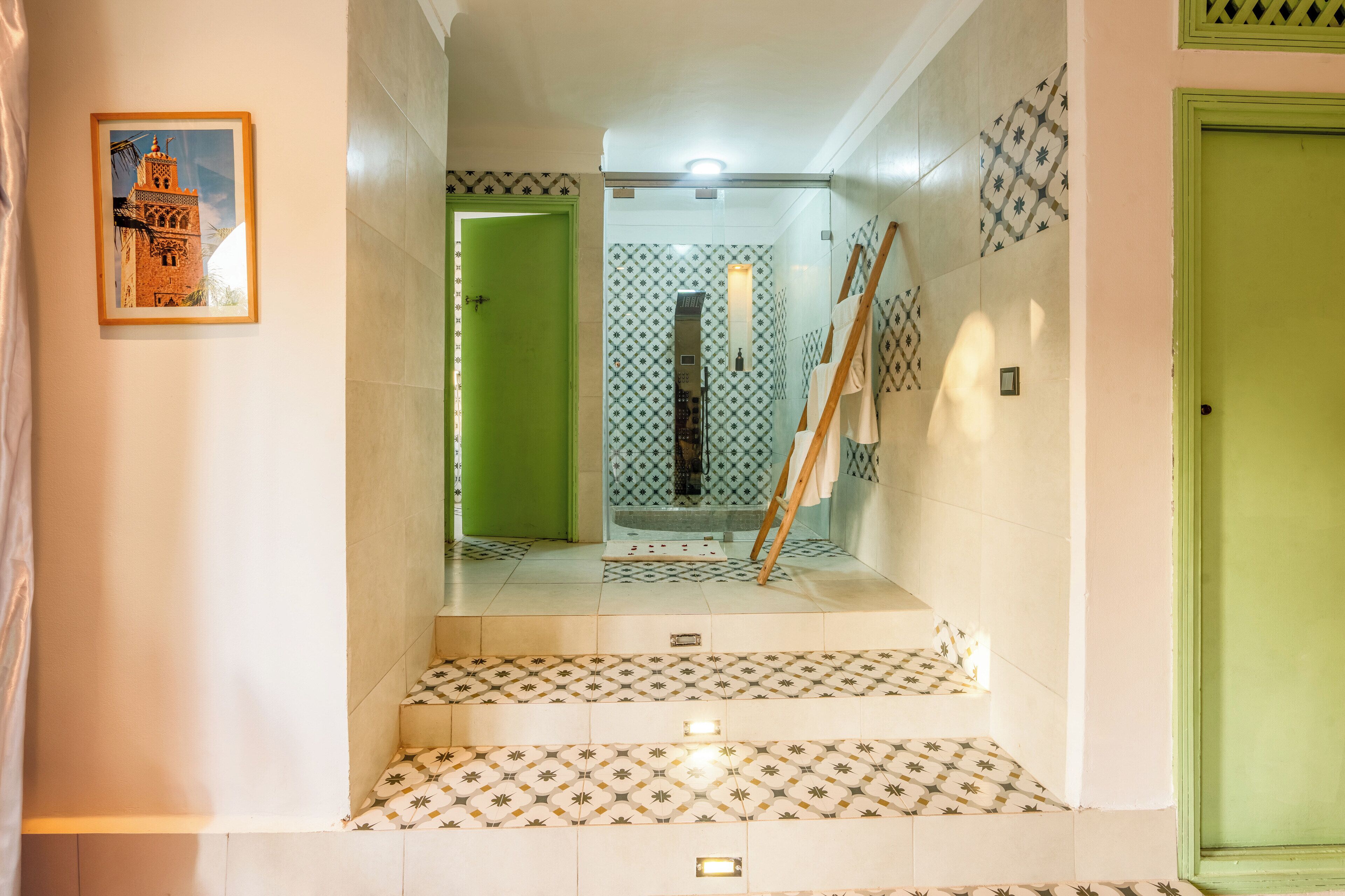 A staircase with patterned tiles leading to a room with a green door and a framed picture on the wall.
