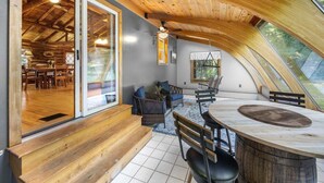 A cozy, wooden interior with a dining area, a seating area with a view of the outdoors, and a large window.