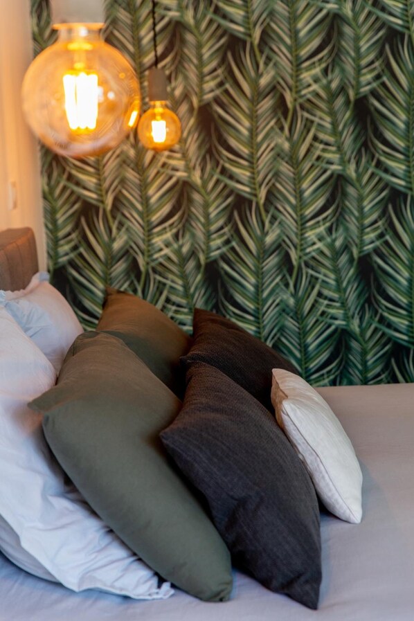 Un lit avec plusieurs oreillers et un mur orné d’un motif de feuilles.