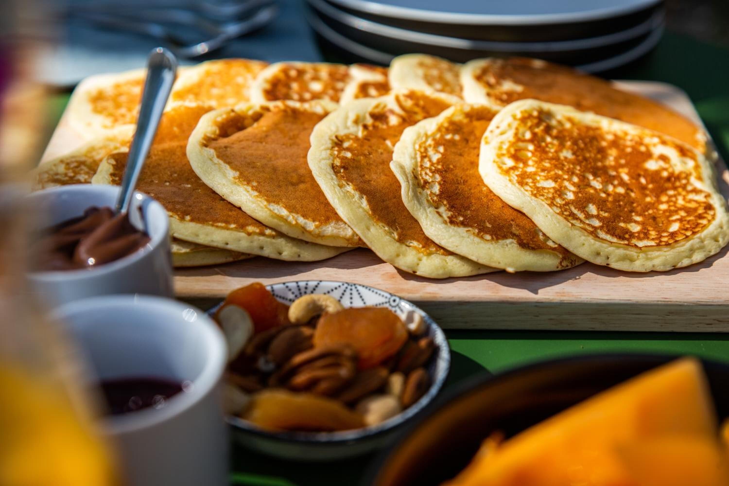 Une table en bois avec des crêpes et un bol de noix.