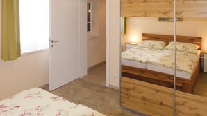Un dormitorio con cama de madera, un espejo y una puerta que da a un baño.