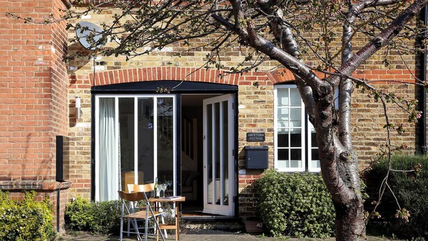 A brick building with a glass door entrance, a wooden bench outside, and a sign reading 'Half Turn Cottage.' - 2 bedroom accommodation in Whitstable (Whitstable)