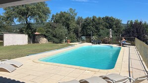 Una piscina rettangolare con bordi piastrellati, circondata da lettini e un'area patio coperta.