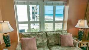 A living room with a sofa, two lamps, and a view of a beach and buildings. - MVG 504 3 BEDROOM 3 BATH OCEANFRONT CORNER (North Myrtle Beach)
