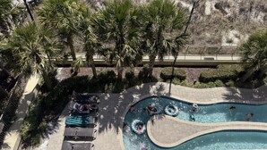 A pool area with lounge chairs, palm trees, and a wooden deck. - MVG 504 3 BEDROOM 3 BATH OCEANFRONT CORNER (North Myrtle Beach)
