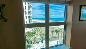 A window with a view of a beach and a building with balconies. - MVG 504 3 BEDROOM 3 BATH OCEANFRONT CORNER (North Myrtle Beach)