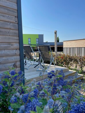 A wooden deck with outdoor seating and a view of a modern building.