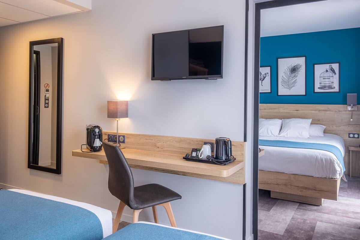 Une chambre d’hôtel équipée d’un bureau, d’une chaise, d’un lit et d’un téléviseur fixé au mur.