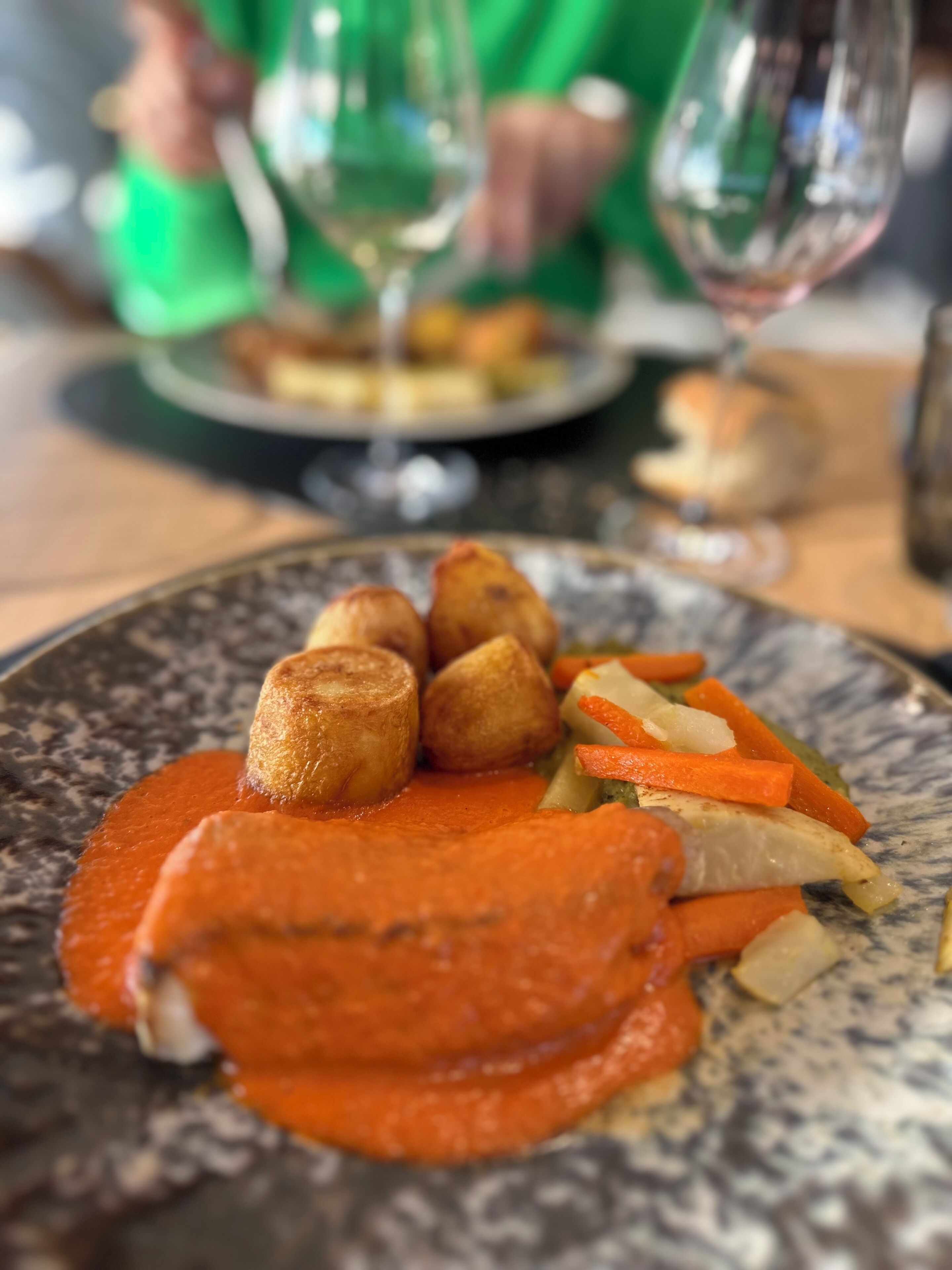 A plate of food with roasted potatoes, carrots, and a red sauce.