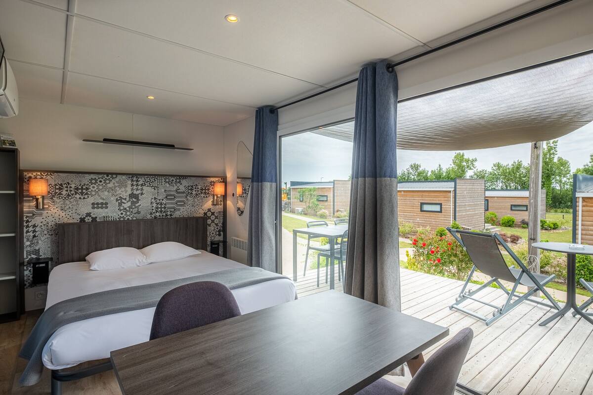 Une chambre d’hôtel moderne dotée d’un grand lit, d’un bureau et d’un balcon avec coin salon ext érieur.