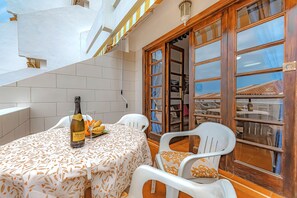 A small outdoor dining area with a table set for two, a bottle of wine, and a view through a wooden door. - 1 bdr apartment with heated pool, close to the beach, Complex Garden City  (Costa Adeje)