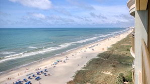 A beach with umbrellas and people, a clear sky, and a view of the ocean. - MVG 1404 Oceanfront Corner Penthouse (North Myrtle Beach)