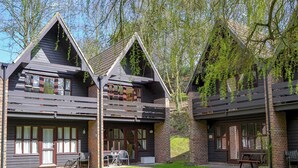 A two-story lodge with a symmetrical design, featuring a central entrance and a covered outdoor seating area. - 3 bedroom accommodation in Cromer (Cromer)