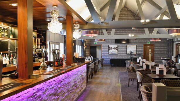 A bar area with a stone wall, wooden beams, and hanging chandeliers. - 3 bedroom accommodation in Cromer (Cromer)