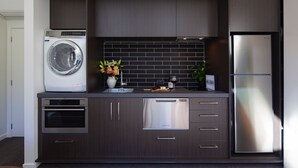 A compact kitchen with a built-in washer, oven, dishwasher, and refrigerator. - The Arrow Nest - Beautiful Stylish Apartment (Arrowtown)