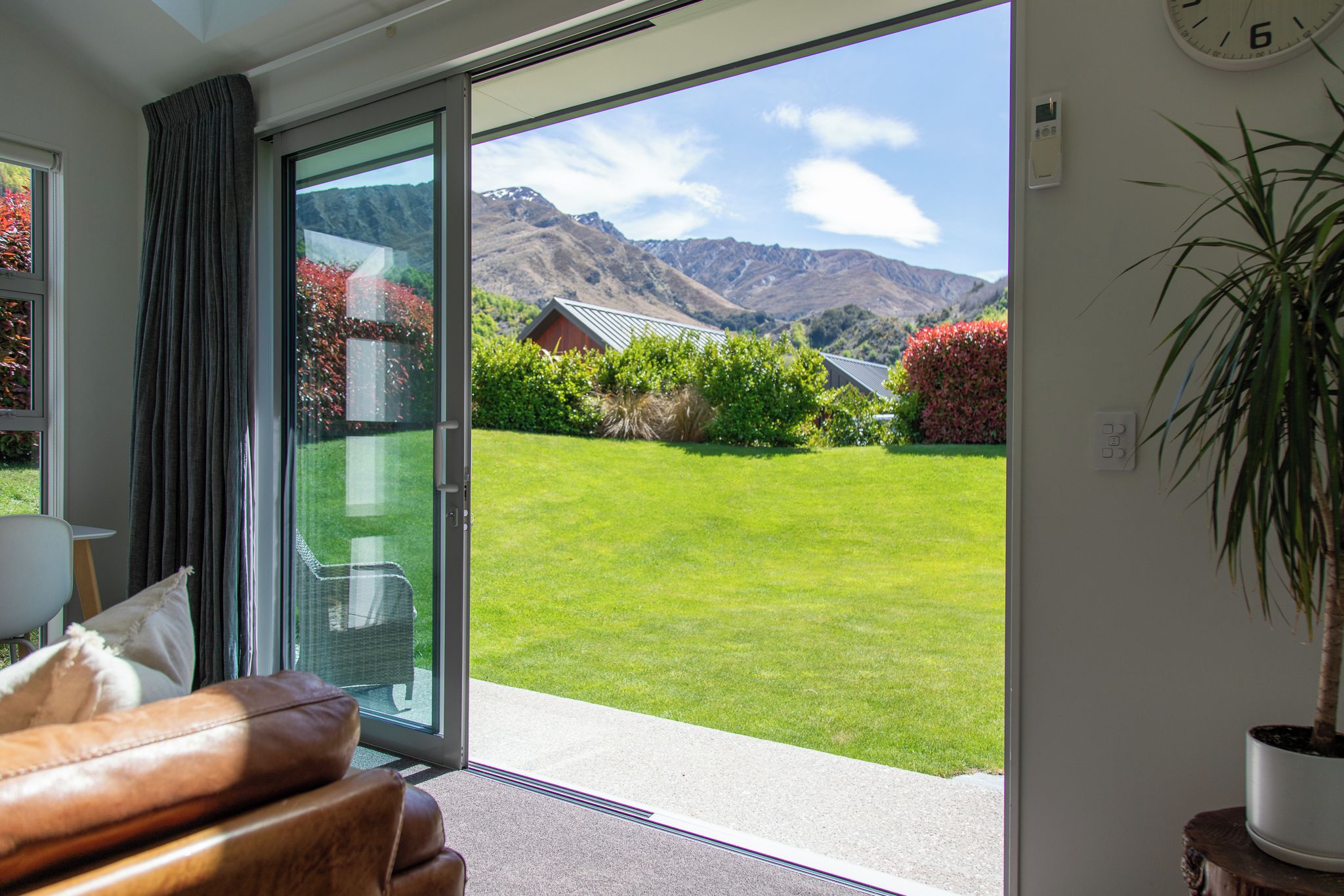 Una habitación con puerta de vidrio corrediza que da a un césped cuidado y vistas a la montaña.