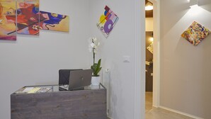 A reception area with a desk, laptop, and a potted plant. - Better & Better (Palermo)