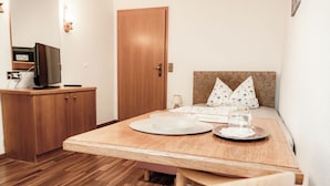 A small, neatly arranged room with a wooden desk, a bed with patterned pillows, and a television on a cabinet. - Gasthaus Hotel Anker (Konstanz)