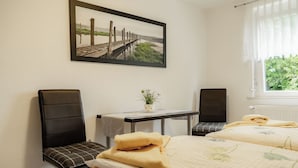 A hotel room with two beds, a small table with a plant, two chairs, and a framed picture on the wall. - Gasthaus Hotel Anker (Konstanz)